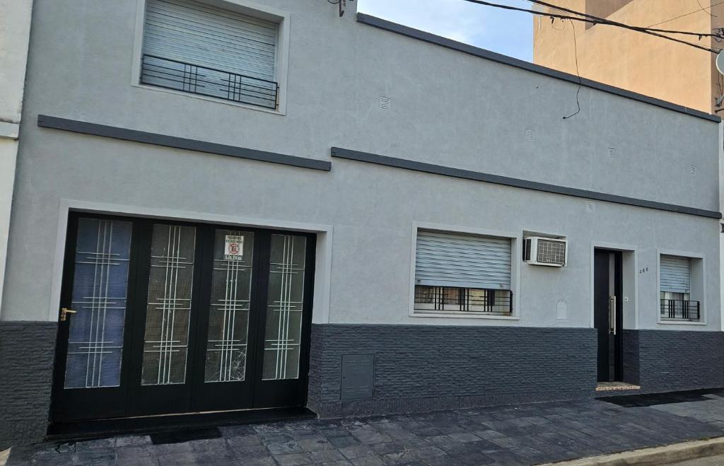 un edificio blanco con puertas y ventanas negras en REST HOUSE Casa familiar - garage - TV - WiFi - 2 dormitorios - Living-comedor - Cocina - Lavadero - Patio con parrilla - Alquiler temporario en Concepción del Uruguay