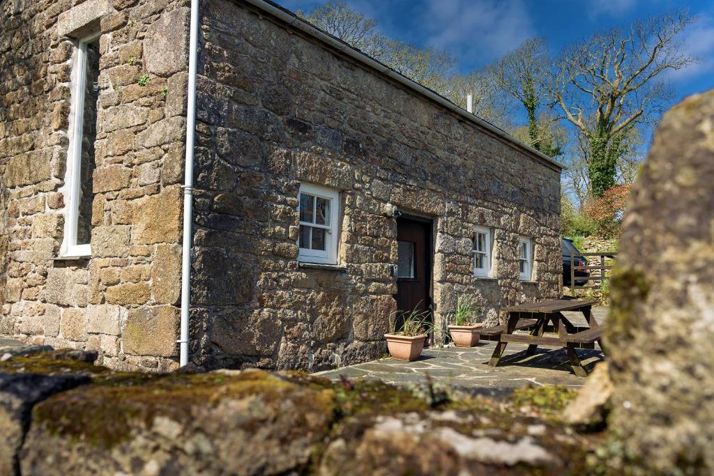 un edificio de piedra con una mesa de picnic delante de él en Beautiful Cornish barn in the stunning Lamorna valley with large garden, en Paul