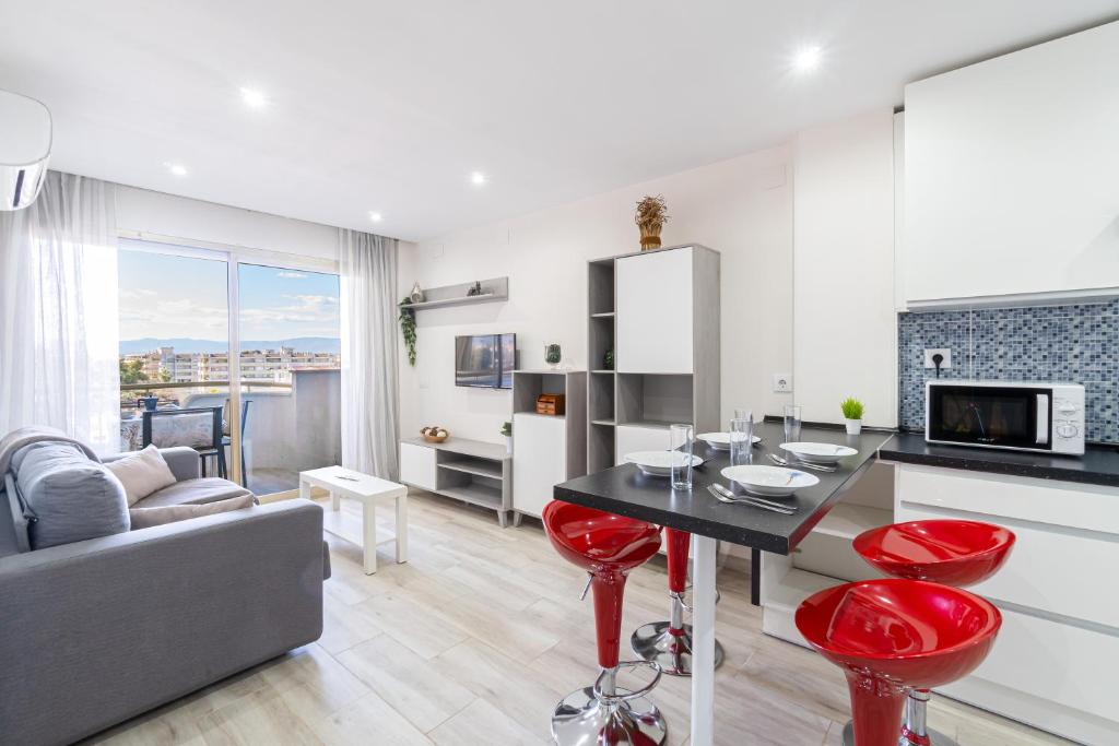 a kitchen and living room with a table and red stools at Playa-Piscina-Port Aventura4 in Salou