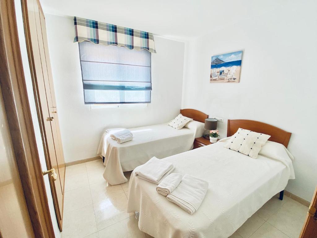 een kamer met 2 bedden en een raam bij Ático frontal con vistas al mar - 1ª línea Acapulco I in Oropesa del Mar