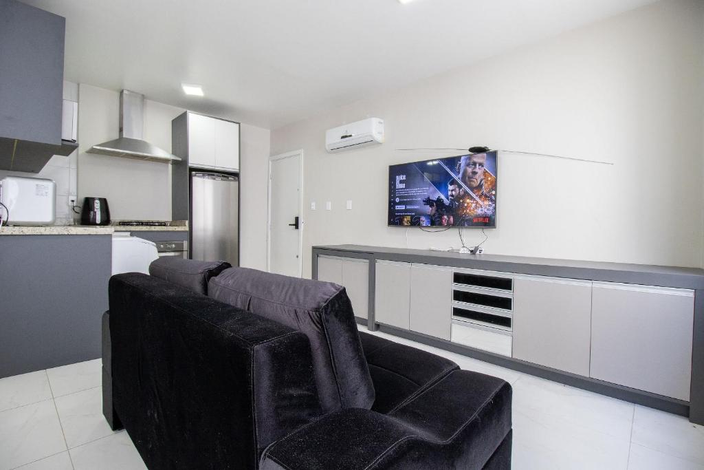 a living room with two chairs and a kitchen at POS25B - Climatizado, TV Smart, Garagem, Wi-Fi in Balneário Camboriú