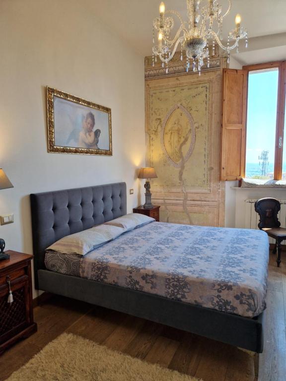 a bedroom with a king sized bed and a chandelier at “Attico Garibaldi” nel cuore della Toscana in Sinalunga