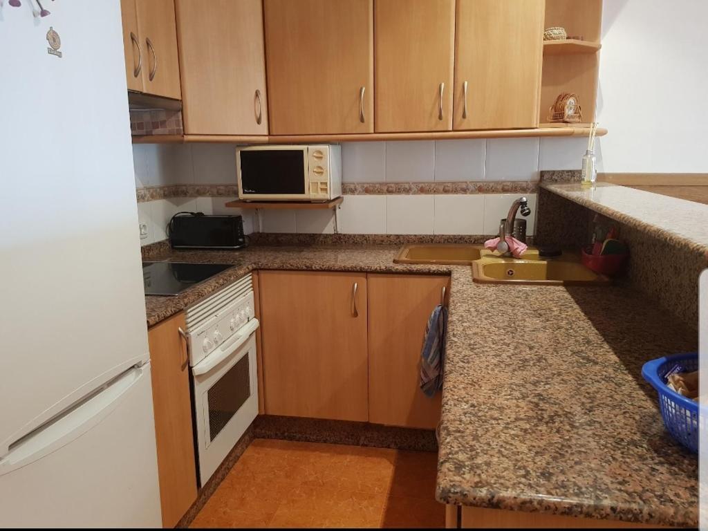 a kitchen with wooden cabinets and a counter top at Apartamento daimus in Daimuz