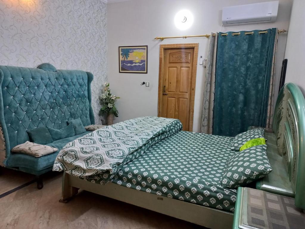 a bedroom with a bed and a blue couch at 3 Bedroom House right In-between Twin Cities in Rawalpindi