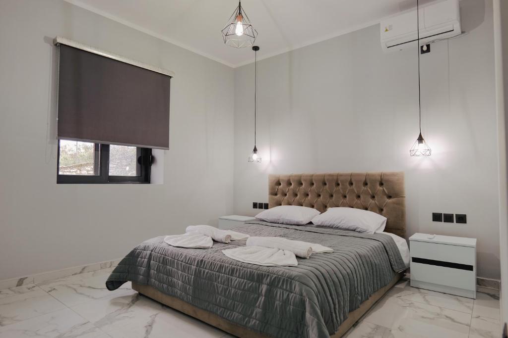 a white bedroom with a large bed with two pillows at Iphigenia Luxury Flat in Sarandë