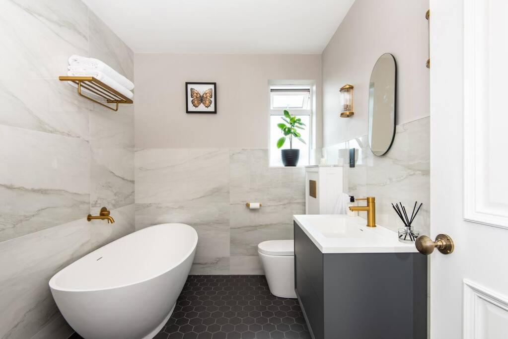 a bathroom with a white tub and a toilet and a sink at Newly renovated Victorian house with free parking in Portslade