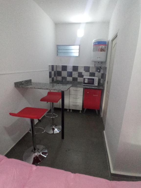 una pequeña cocina con 2 taburetes rojos y una barra en Departamento Marques, en Santa Rosa