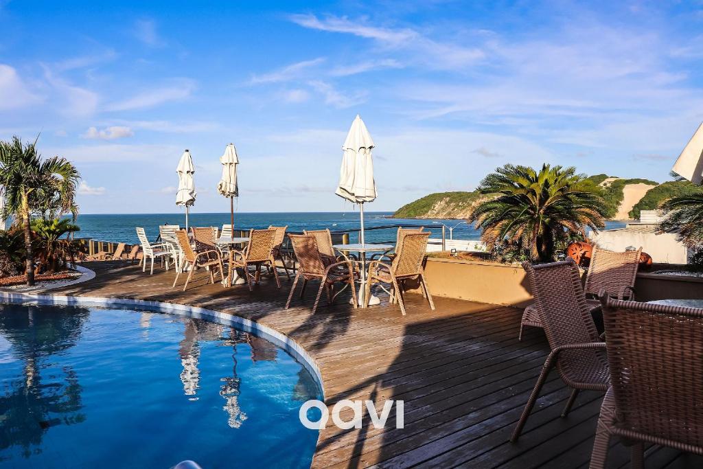 een zwembad met stoelen en parasols naast de oceaan bij Mirador Apart-hotel por Quarto à Vista in Natal