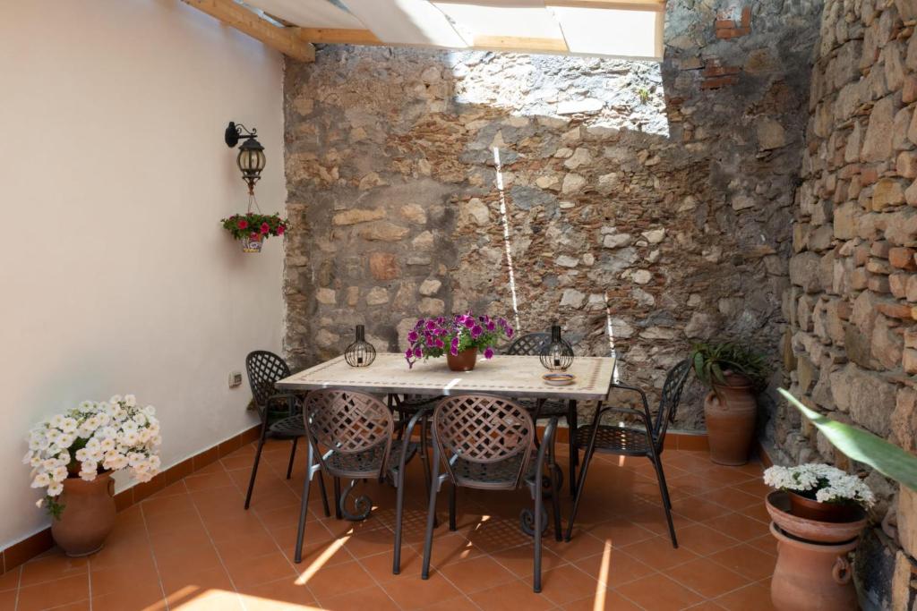 a table and chairs in a room with a stone wall at B&B RE TANCREDI in Taormina
