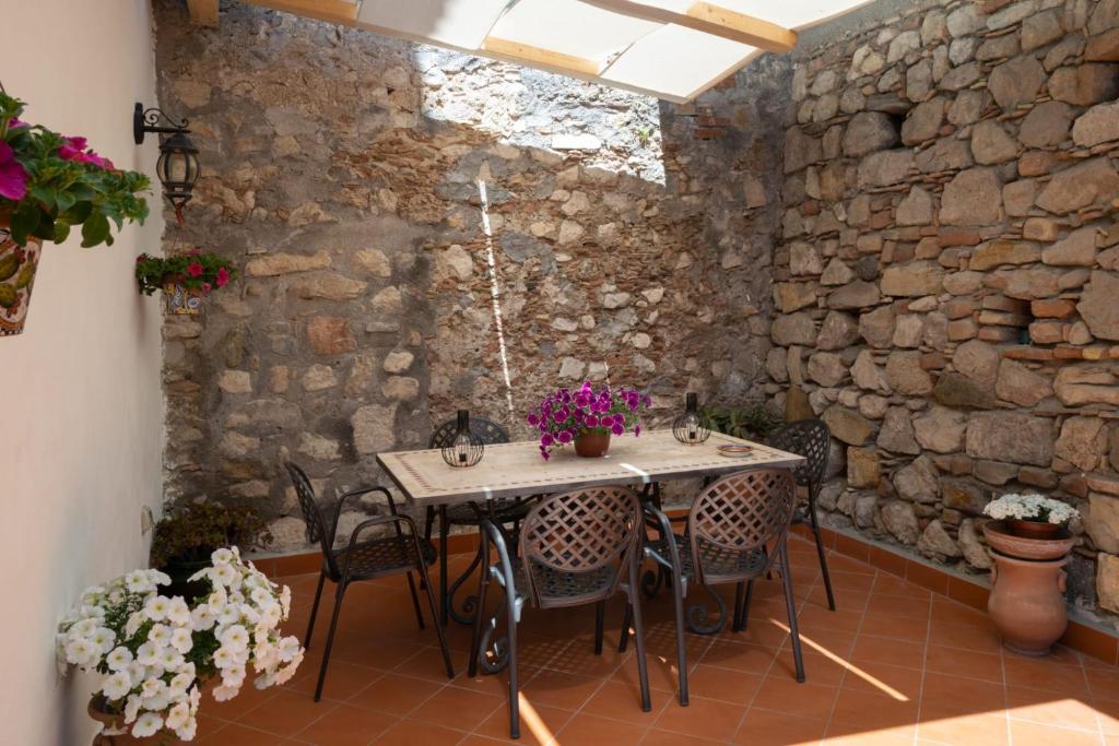 a table and chairs in a room with a stone wall at B&B RE TANCREDI in Taormina