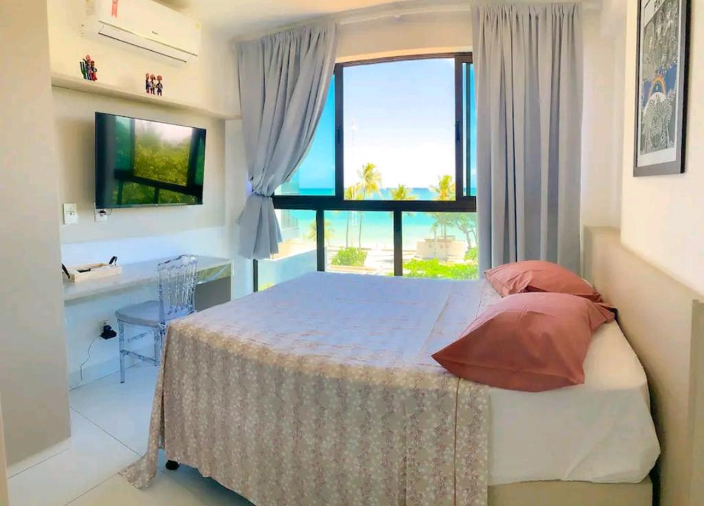 1 dormitorio con cama y ventana grande en Belo Flat à beira mar en Recife