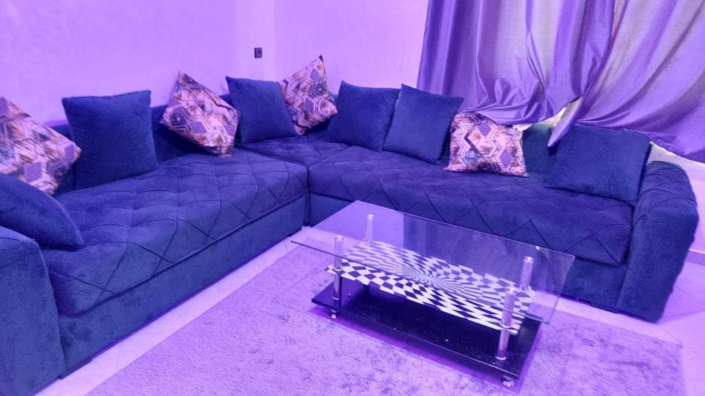 ein Wohnzimmer mit einem blauen Sofa und einem Tisch in der Unterkunft Appartements ESSALAM 1 in El Aaiún