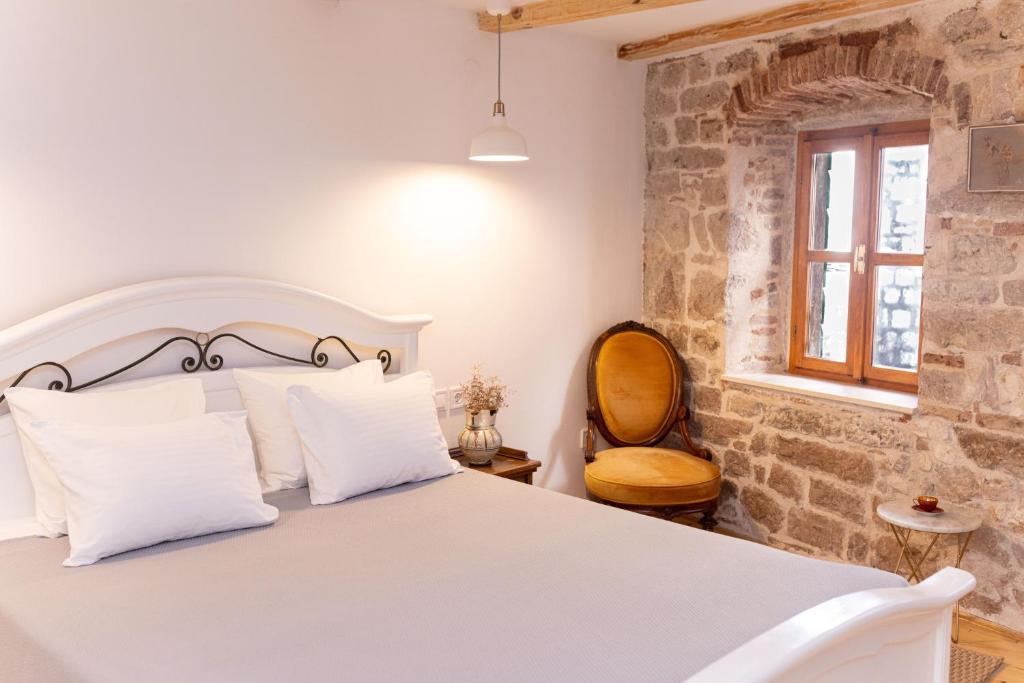 a bedroom with a white bed and a chair at Casa Milina in Šibenik