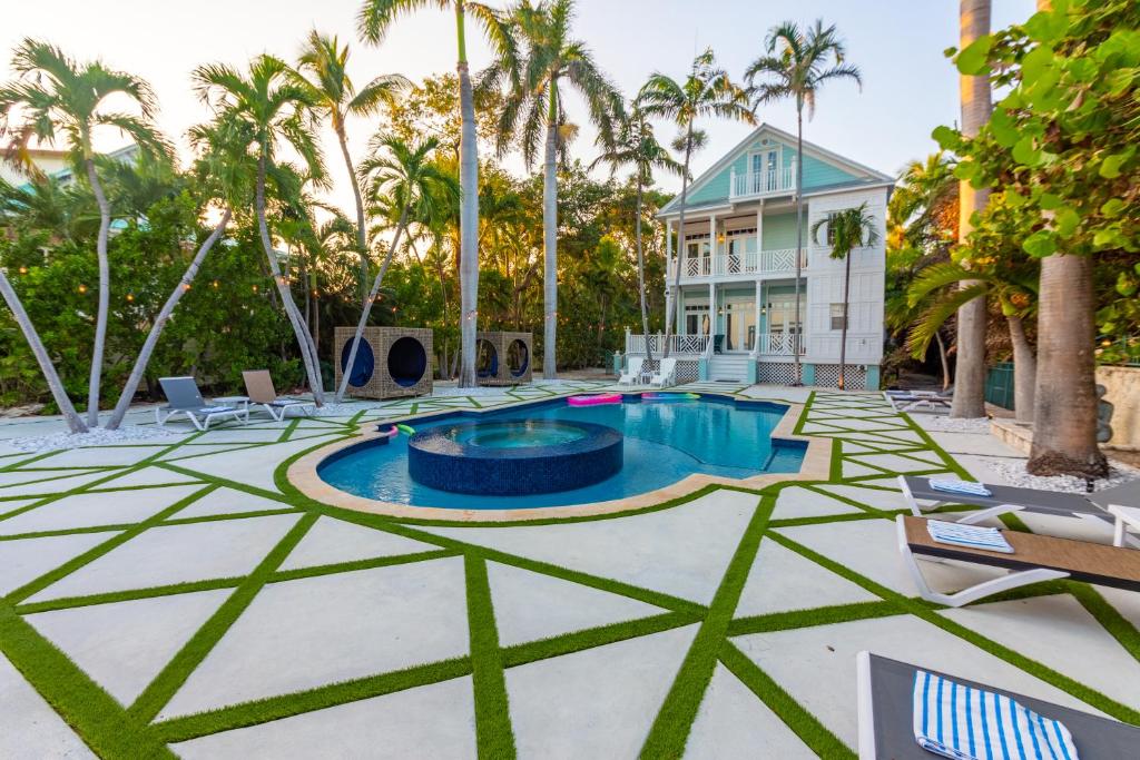 a pool with palm trees and a house at Beachfront Villa at Islamorada BY THE GLAMHOMES in Islamorada