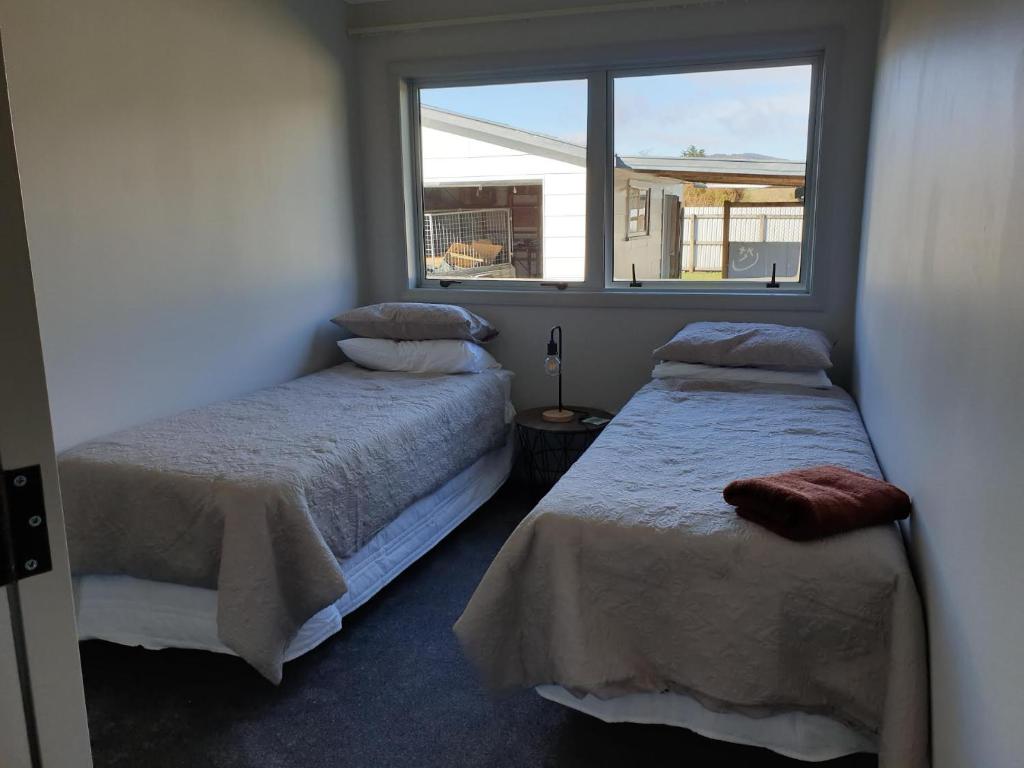 two beds in a room with a window at Kiwiana Gem in Reefton