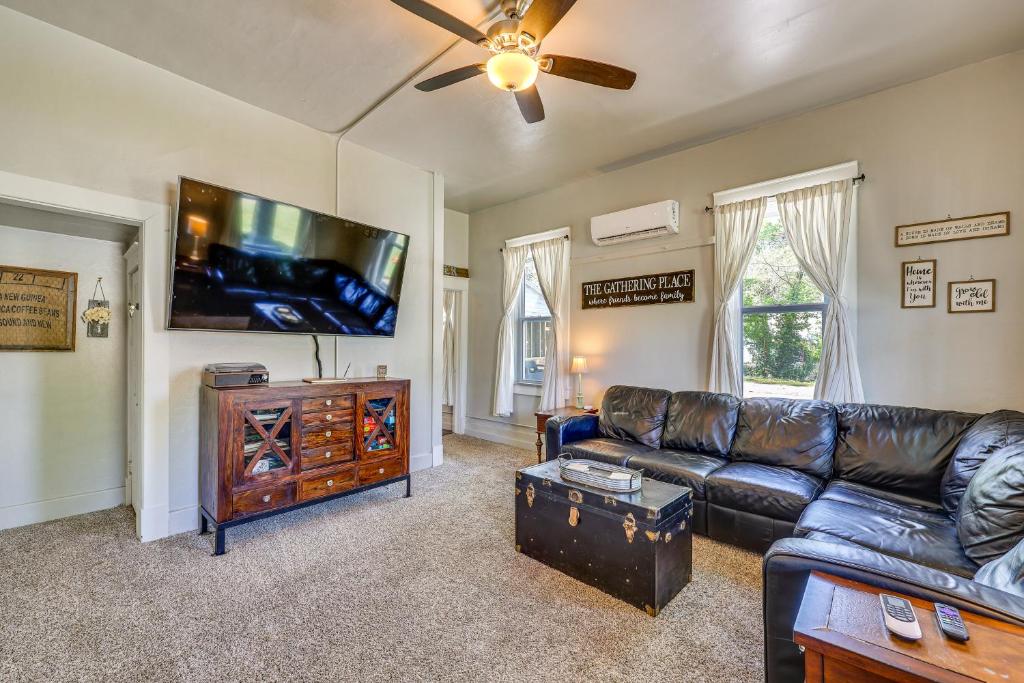 a living room with a leather couch and a flat screen tv at Cave Springs Home about 16 Mi to Razorback Stadium! in Lowell