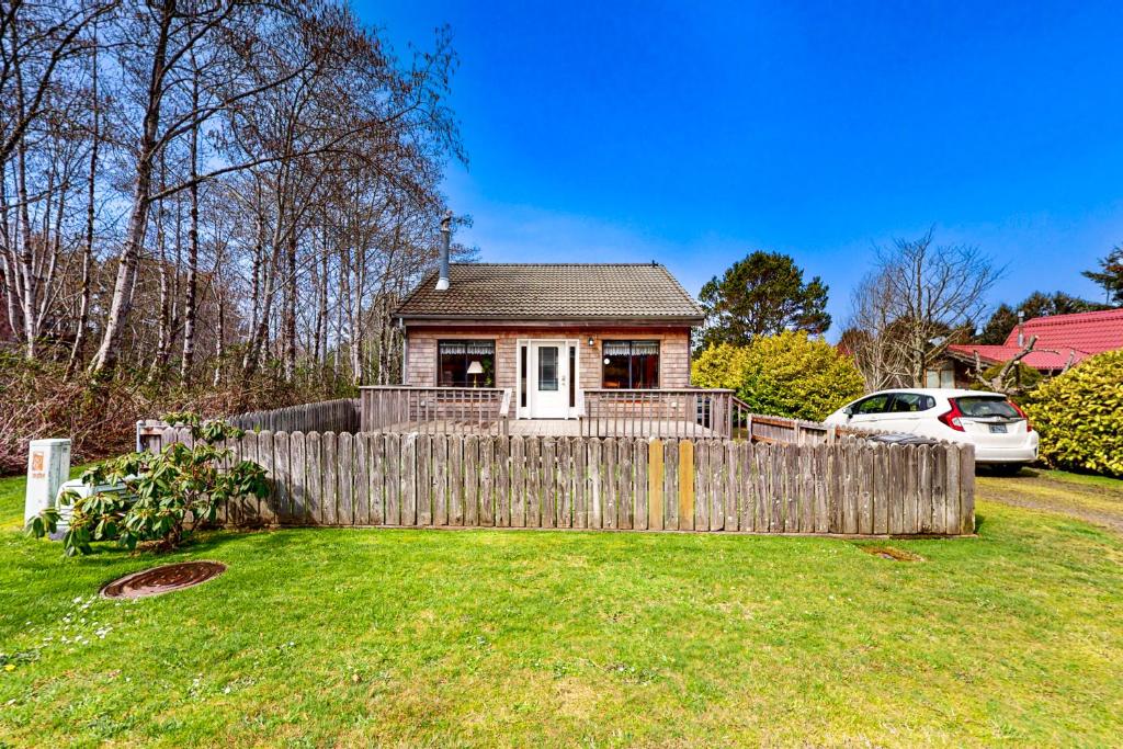 una pequeña casa detrás de una valla en un patio en Cannon Beach Cottage en Cannon Beach