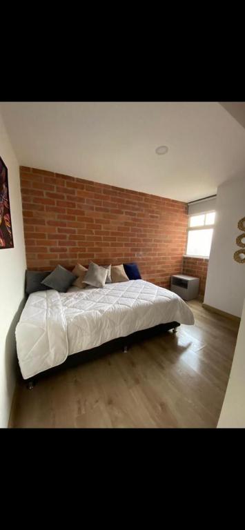 - une chambre avec un lit blanc et un mur en briques dans l'établissement Apartamento amplio y confortable, à Medellín