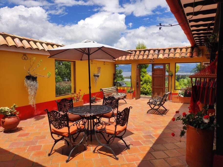 patio con tavolo, sedie e ombrellone di Casa Finca El Mirador frente a la laguna de Fúquene a Fúquene