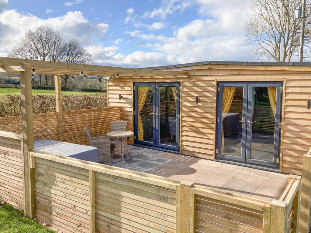 a wooden cabin with a deck with a table and chairs at Swallow Lodge - Uk42540 in Winforton