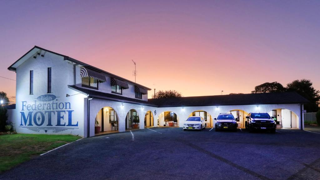 un edificio con tres coches estacionados en un estacionamiento en Parkes Federation Motel en Parkes