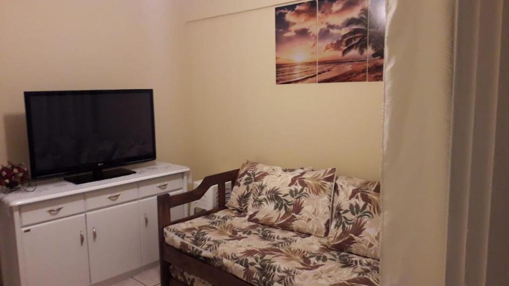 a living room with a couch and a flat screen tv at Lindo apartamento em frente a praia in Praia Grande