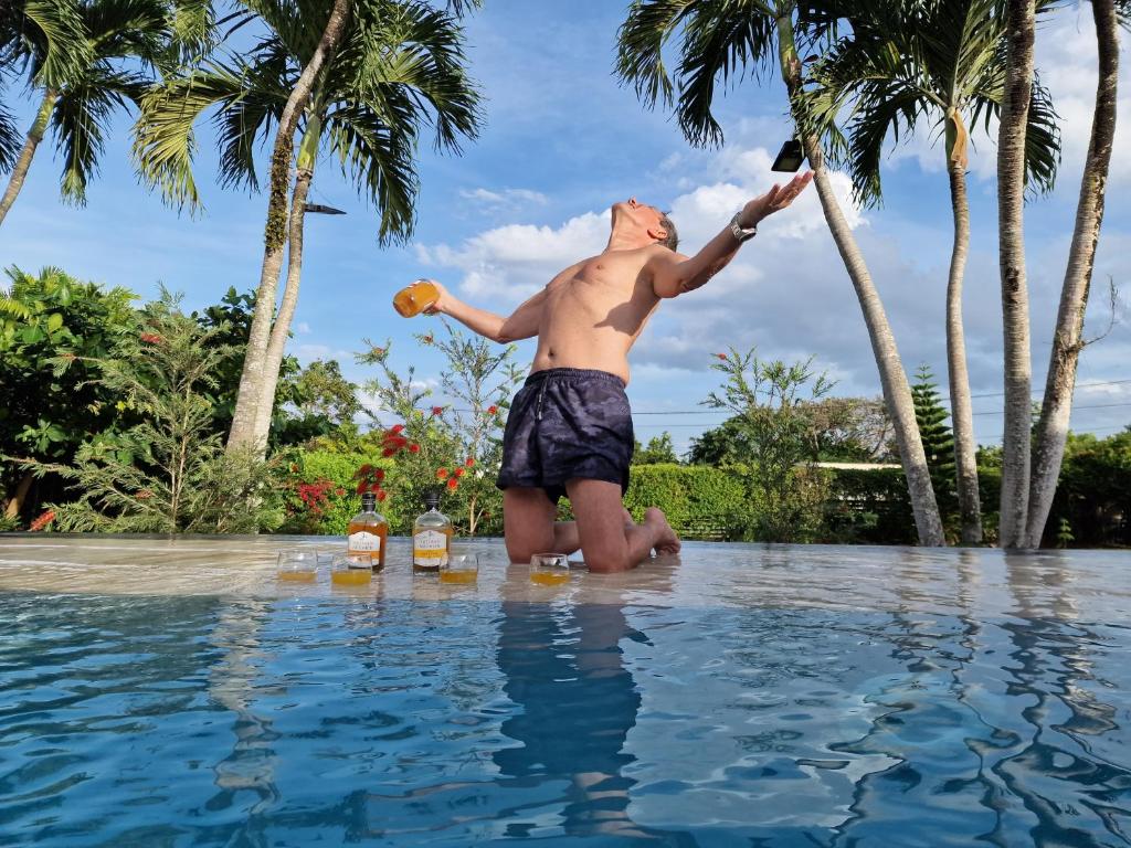 Un uomo in piedi in acqua in una piscina di Appartements de Luxe . Propriété de Luxe a Baie-Mahault