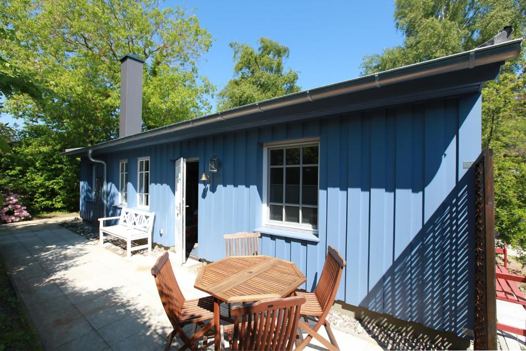 烏斯特羅的住宿－Strandnest，蓝色和白色的小屋,配有桌椅