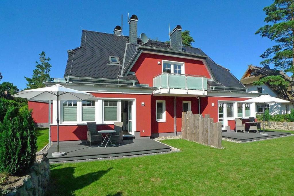 czerwony dom ze stołem i parasolem w obiekcie Haus Dünenrot OG-Whg DR-04 w mieście Neuhaus
