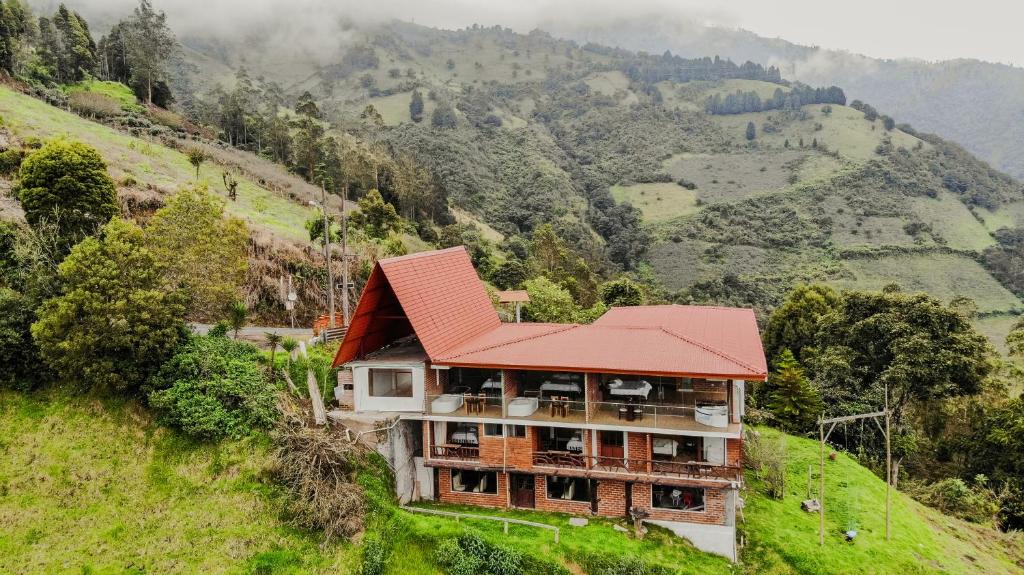 ein Gebäude mit rotem Dach auf einem Hügel in der Unterkunft Casa de Campo El Descanso in Baños