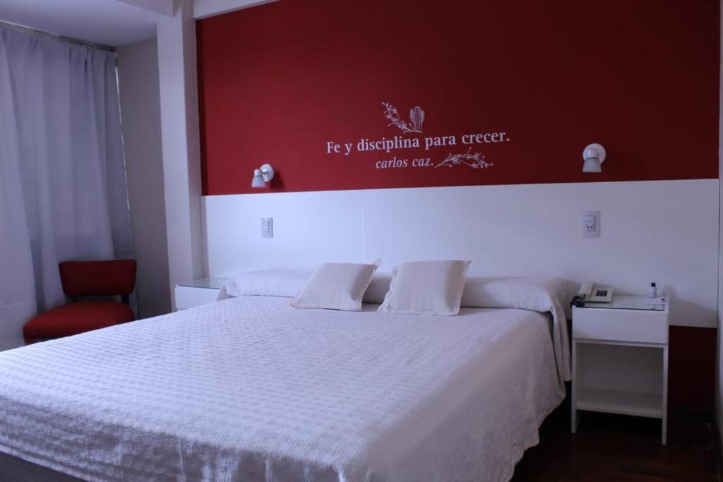 um quarto com uma cama branca e uma parede vermelha em Hotel Ychoalay Caz em Reconquista