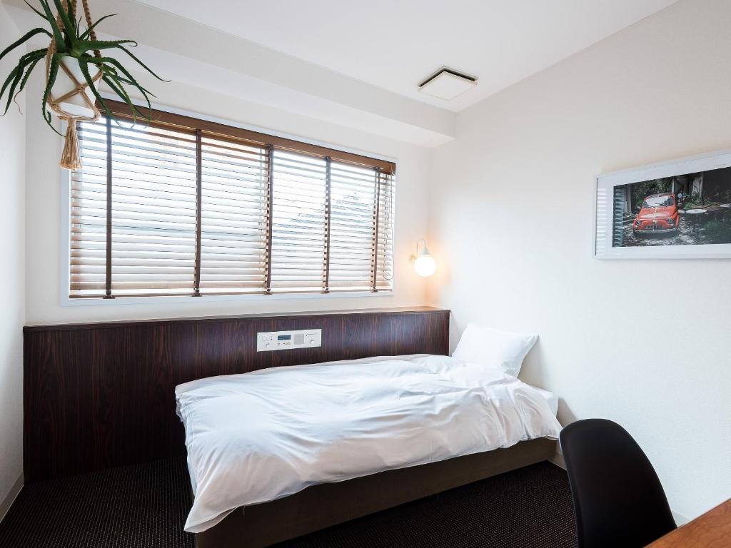a bedroom with a bed with a wooden headboard and a window at Hotel Pacific Kanazawa in Kanazawa