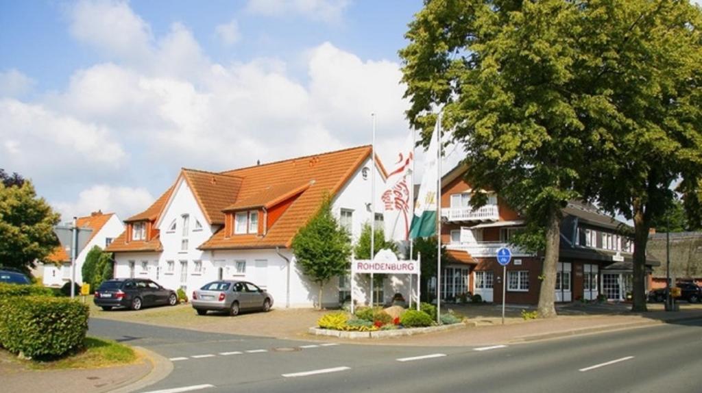 ein großes weißes Gebäude mit orangefarbenem Dach auf einer Straße in der Unterkunft Land-gut-Hotel Rohdenburg in Lilienthal
