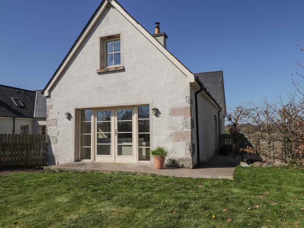 uma casa branca com uma grande porta de vidro deslizante em East Balachladich em Muir of Ord