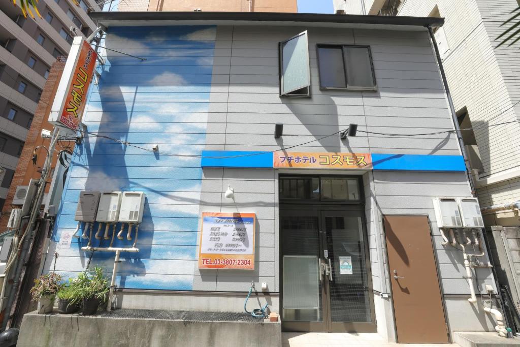 un edificio azul con un cartel en el costado en プチホテル　コスモス, en Tokio
