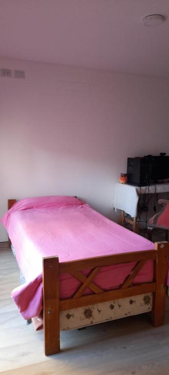 Terraza a la Barda في نيوكين: سرير في غرفة مع بطانية وردية عليه