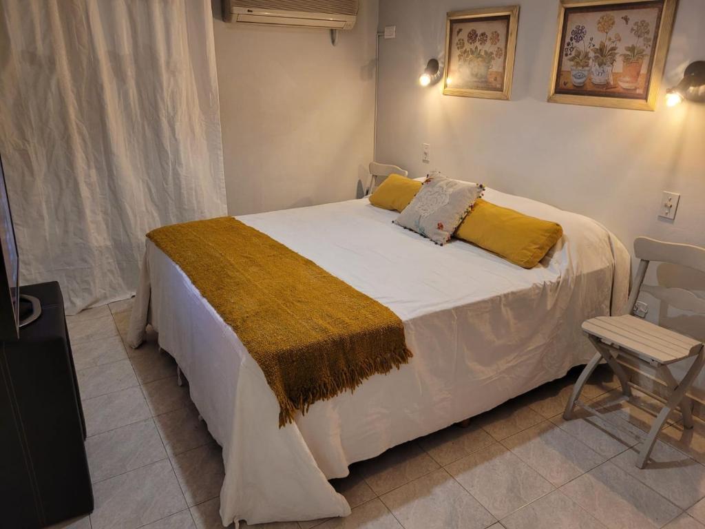 1 dormitorio con 1 cama blanca grande con almohadas amarillas en Torre Salta y Santa Fe en San Miguel de Tucumán