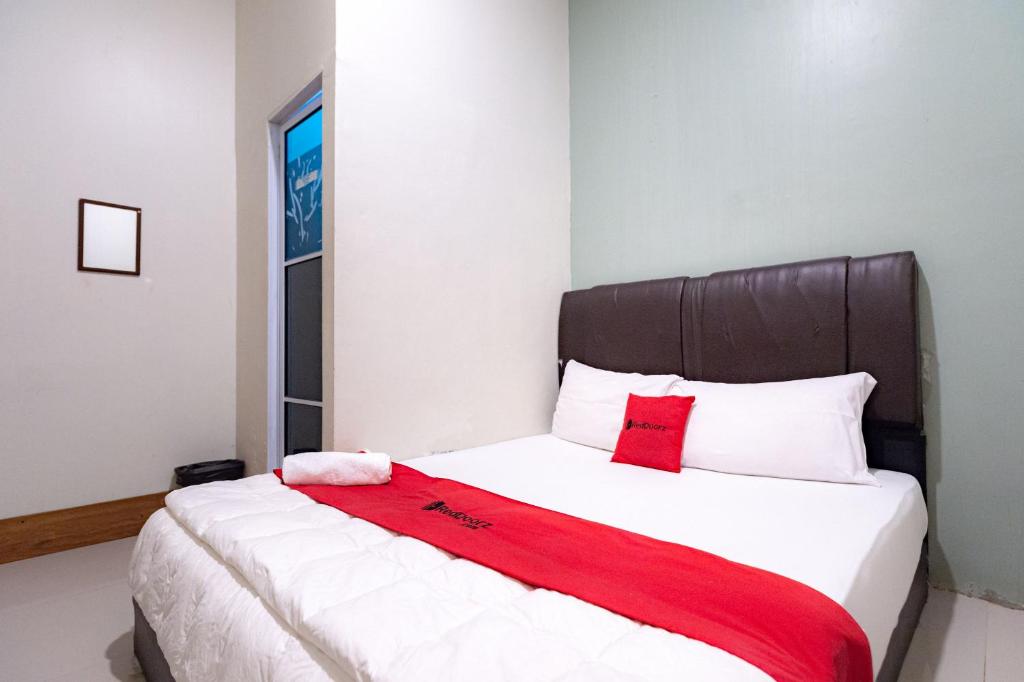 a bedroom with a bed with a red blanket on it at RedDoorz near Hang Nadim Batam Airport in Nongsa