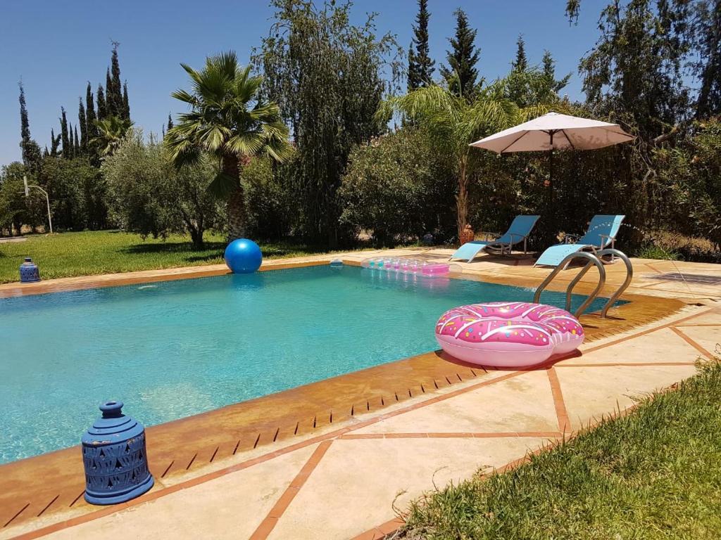 una piscina con sombrilla, silla e inflable en villa Marrakech raja en Marrakech