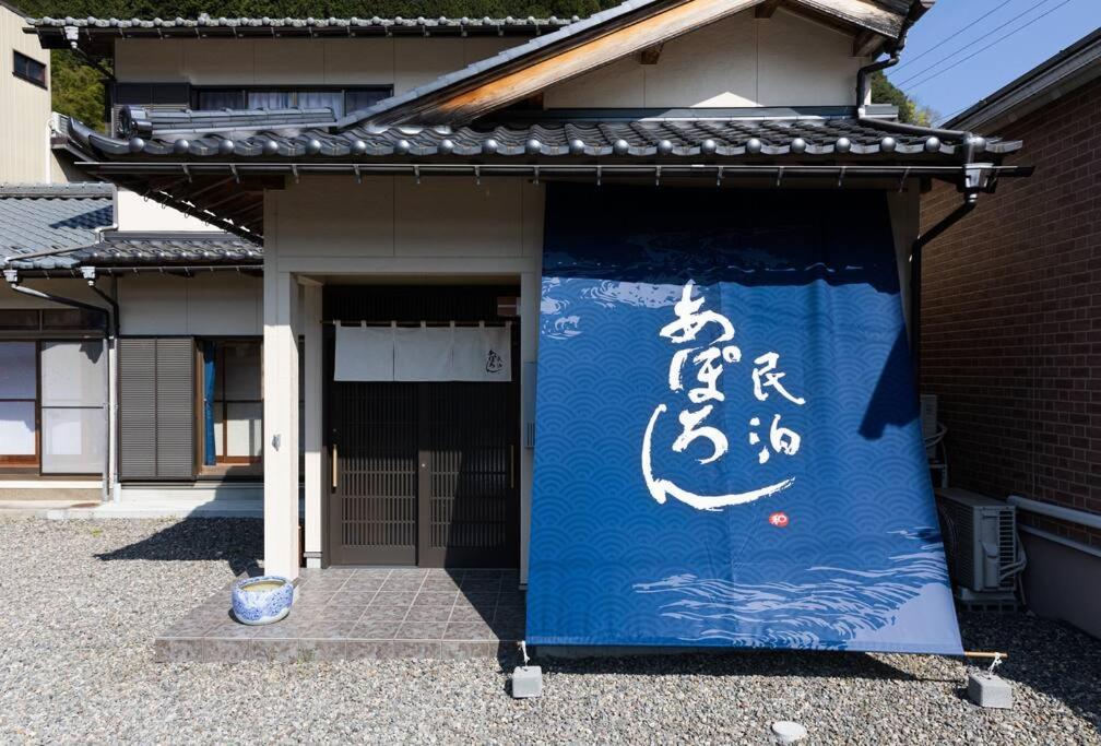 un panneau bleu et blanc sur le côté d'un bâtiment dans l'établissement あぽろん, à Gujō
