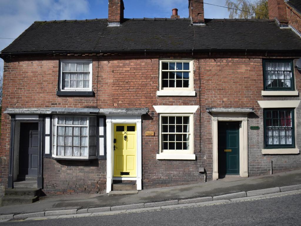 uma casa de tijolos com portas amarelas numa rua em Church View Cottage em Ashbourne