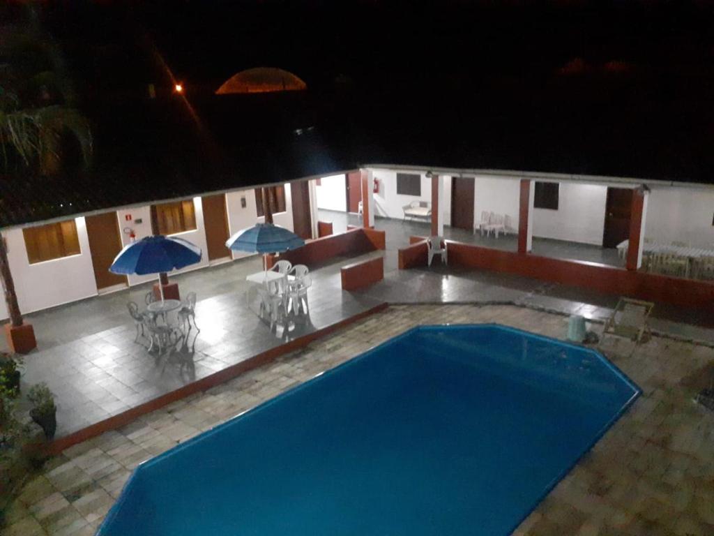 a large blue swimming pool in a building with umbrellas at Pousada Por do Sol in Cananéia