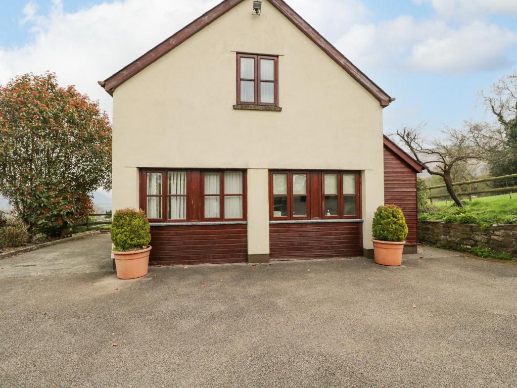 a white house with windows and plants in a driveway at Penrose Cottage in Gilwern