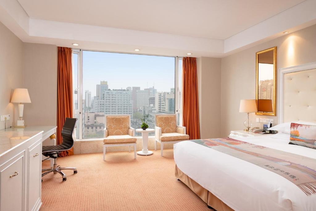 una camera d'albergo con un grande letto e una grande finestra di Hangzhou Xinqiao Hotel a Hangzhou