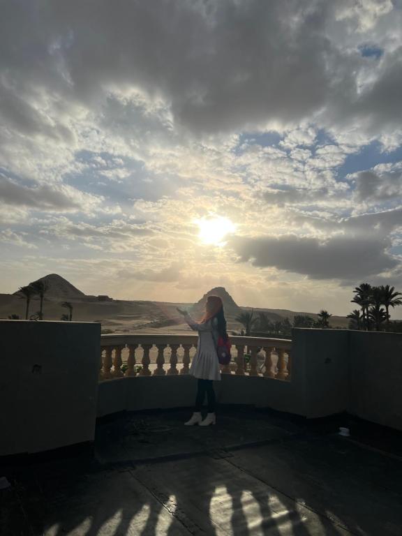 a woman standing on a balcony looking at the sunset at Sunset Guesthouse Abusir in Cairo
