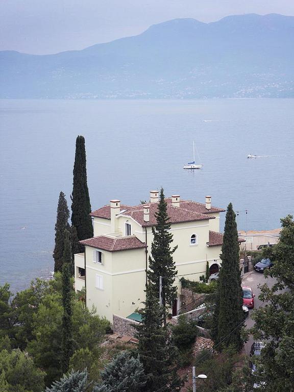 a house on top of a hill next to the water at Apartments Villa Nora in Rijeka