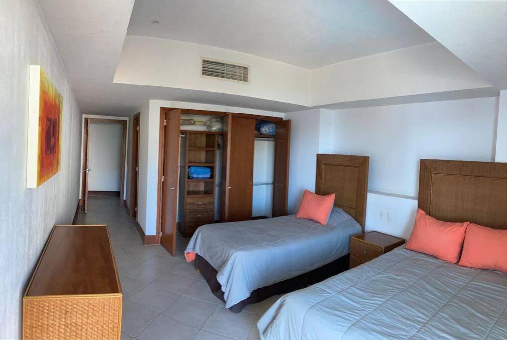 um quarto de hotel com duas camas e uma televisão em Condominio en Ixtapa frente a la playa em Ixtapa