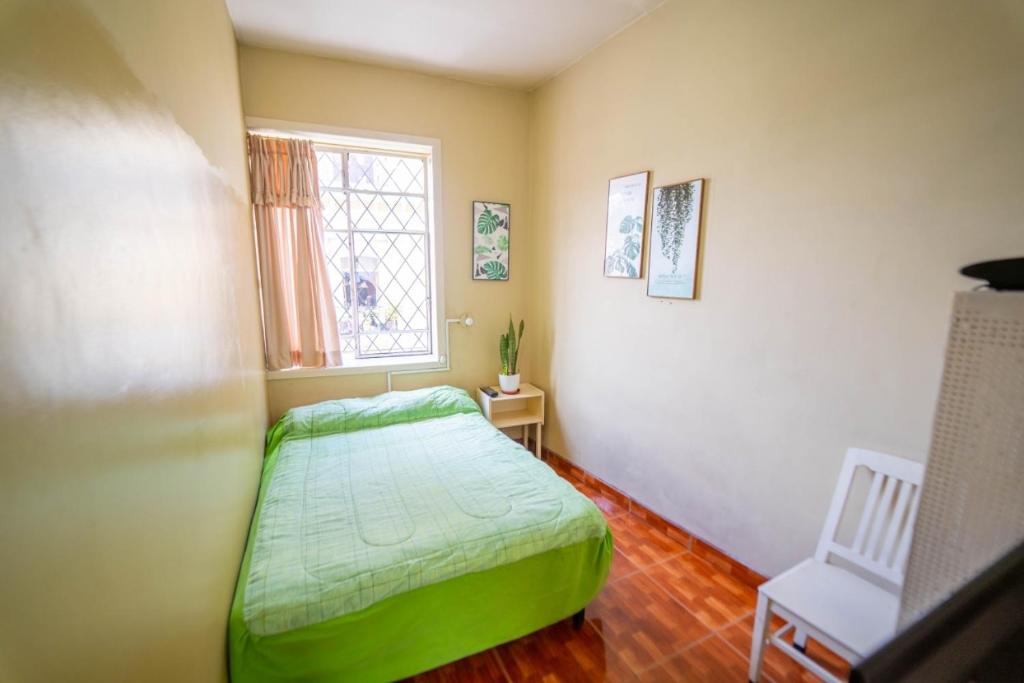 een slaapkamer met een groen bed en een raam bij Casa Mercedes in Quito