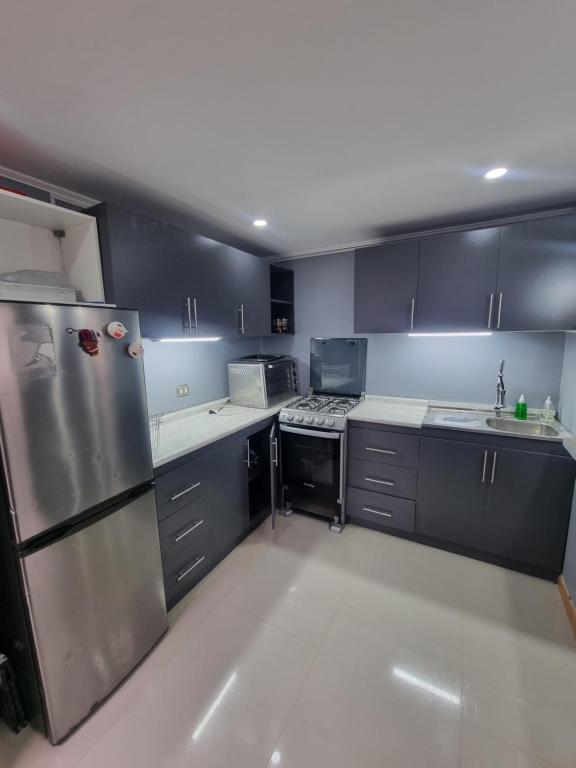 a kitchen with black cabinets and stainless steel appliances at Cabaña in Ancud