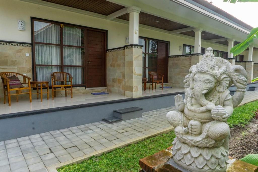 a stone statue in front of a house at Kubu doble in Sanur
